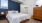 bedroom with white bedding a dresser and small window